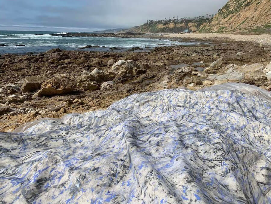 A loose canvas covered in rubbing marks, draped over the rocky beach at White Point.